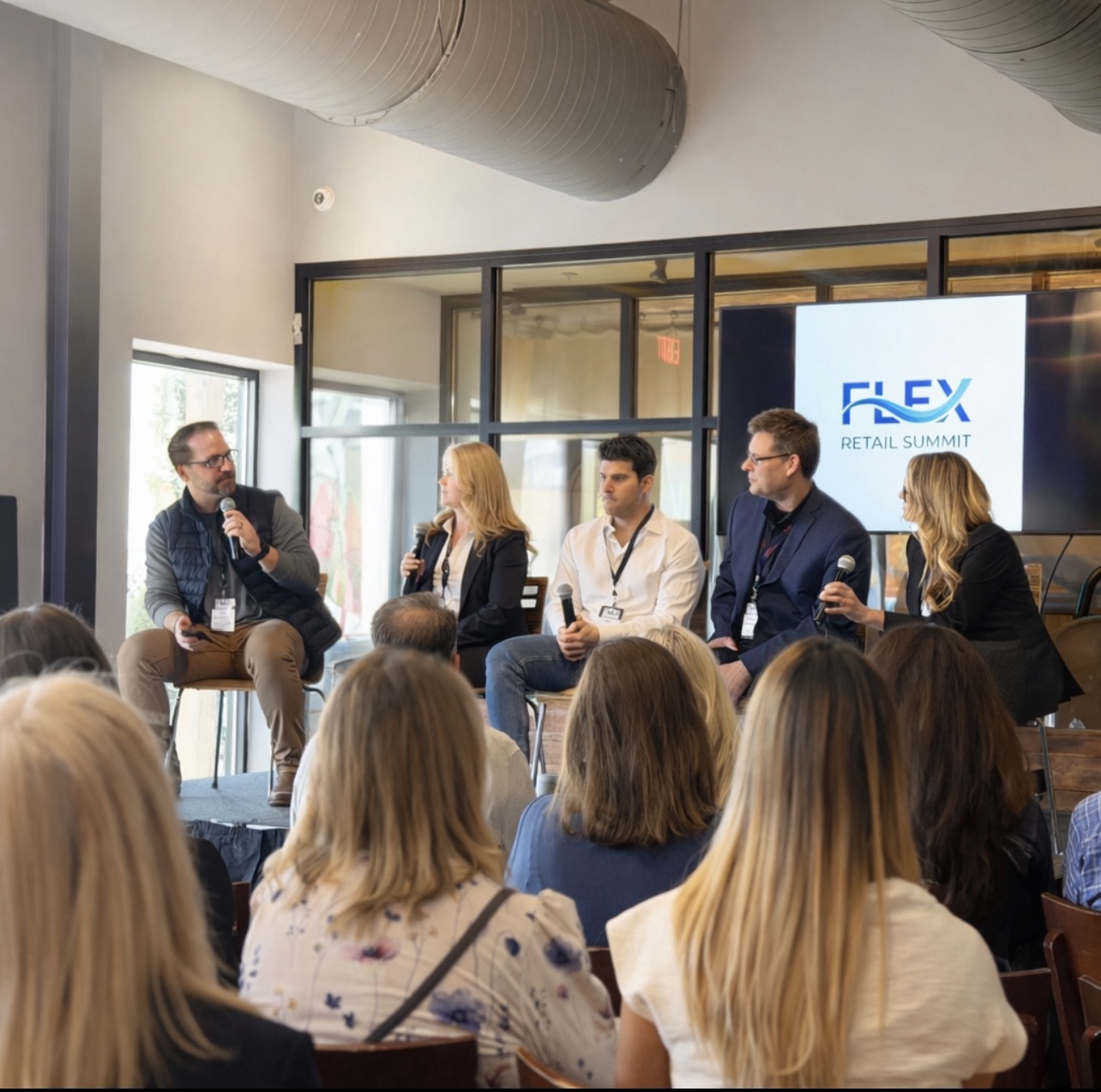 Panel discussion on stage at the FLEX Retail Summit — speakers with microphones in front of an audience